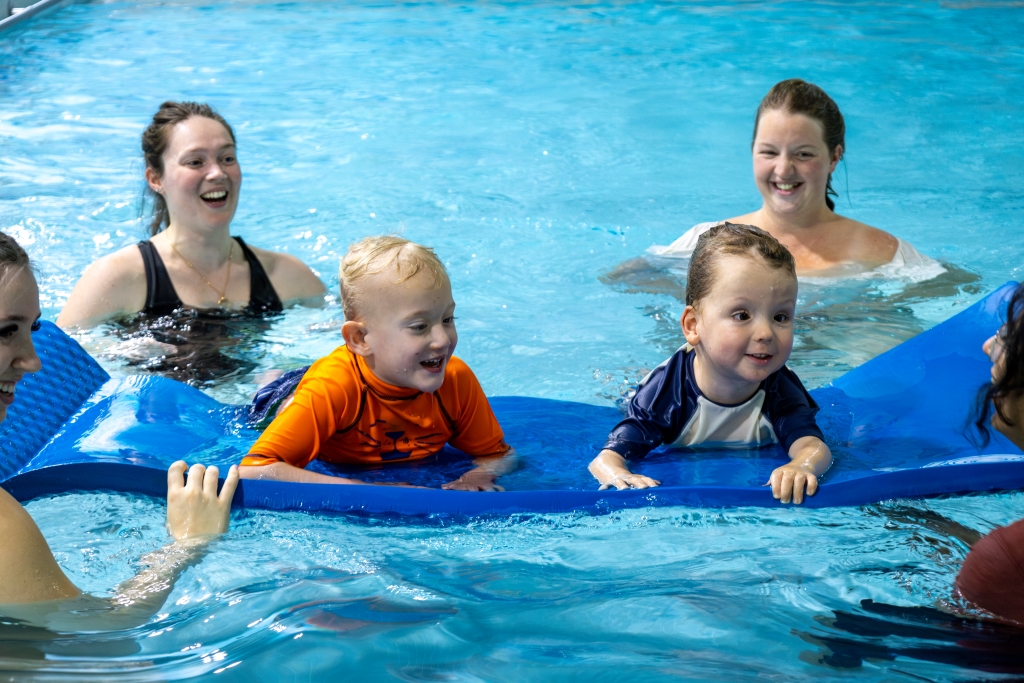 Two boys floating on a mat in a pool