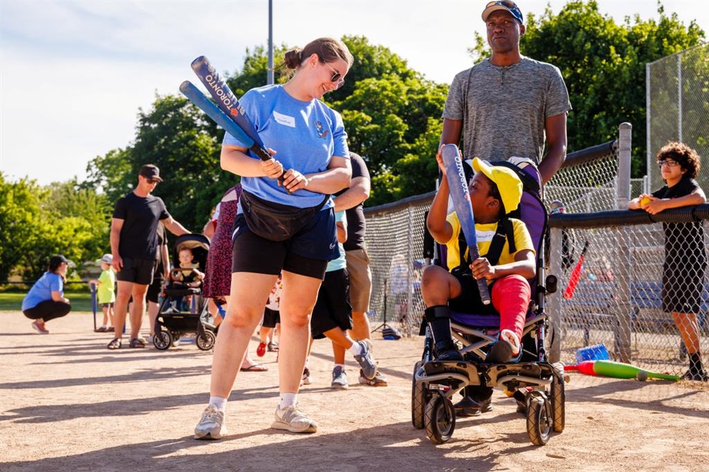 Women holding a baseball bat talking with young boy