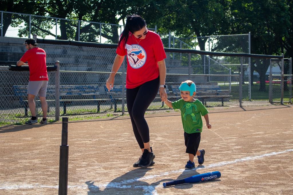 Women running with boy at baseball field
