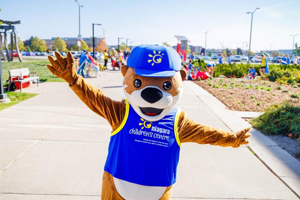 Otter mascot with blue top and blue hat in front of blue sky