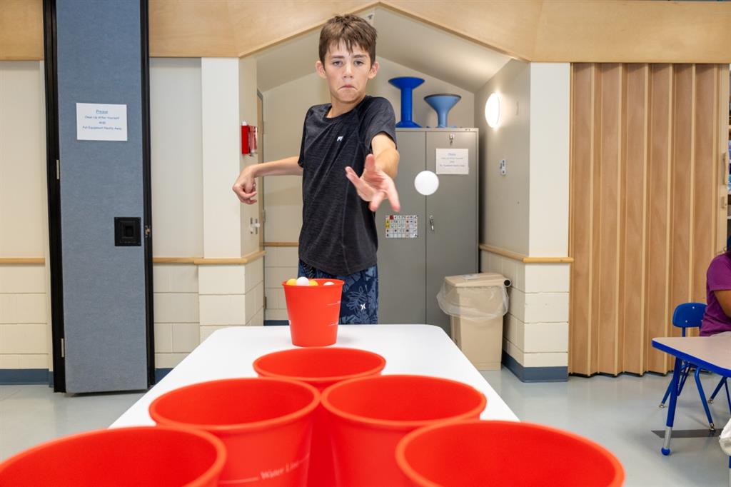 Boy tosses ball into red cup
