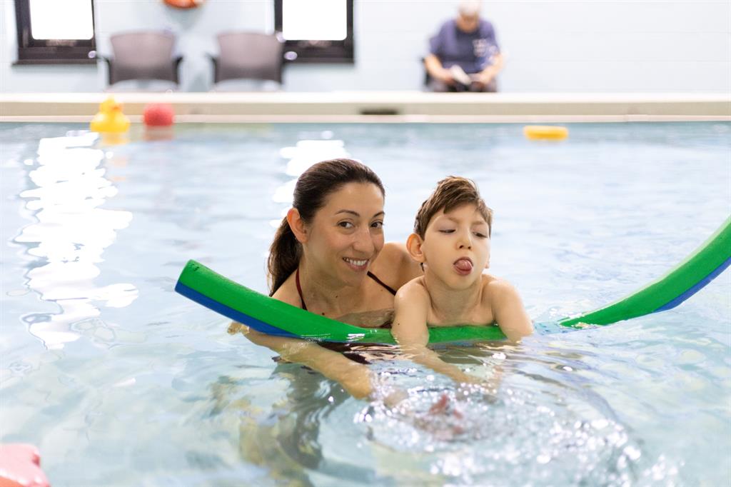 Women and young boy swim in a pool
