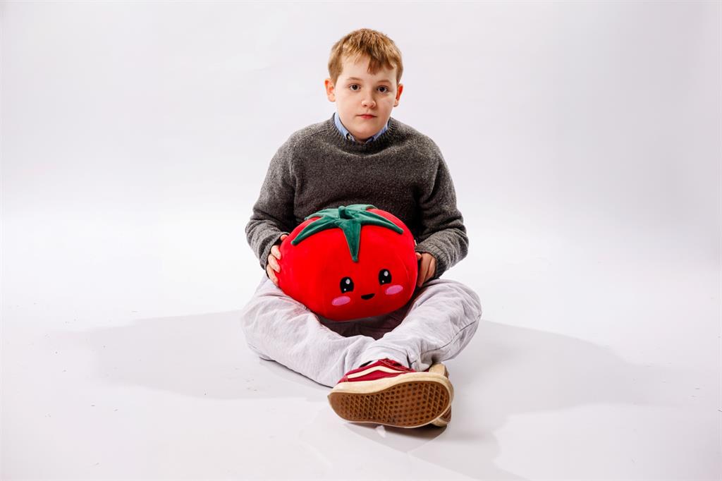 Young boy sitting cross legged in front of a white backdrop