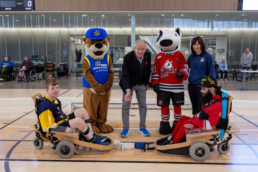 Man drops a ball in between two players for a face off
