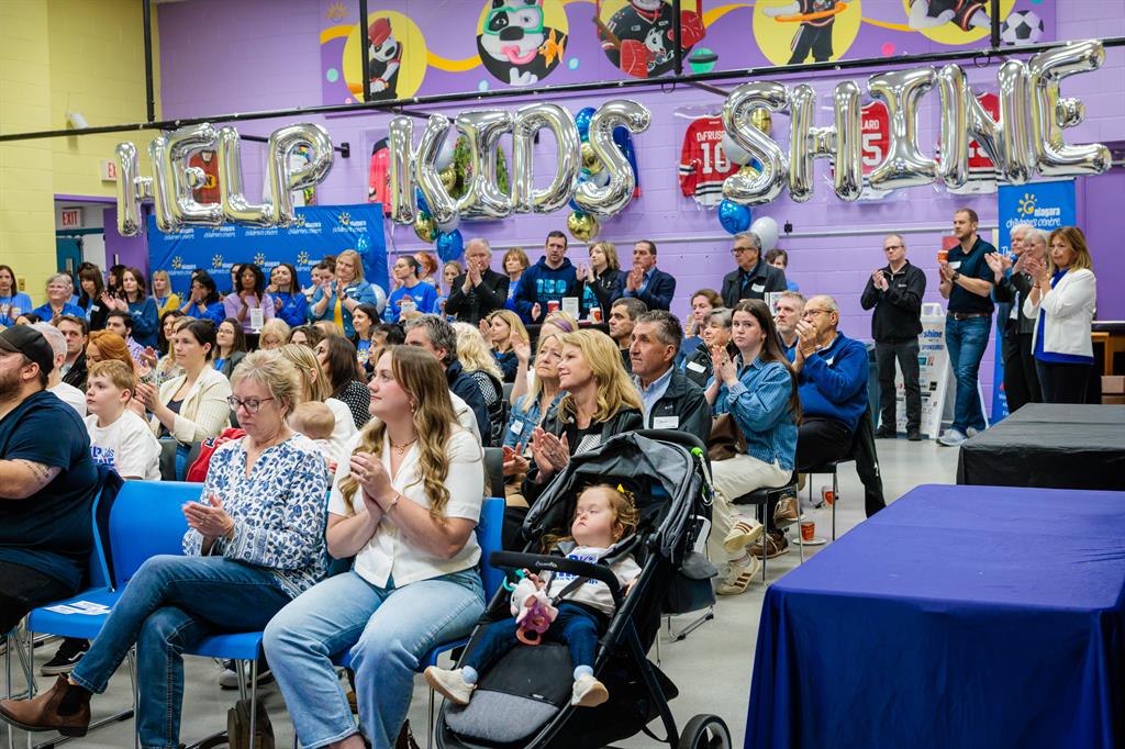 A crowd of 100 people sitting in a gym