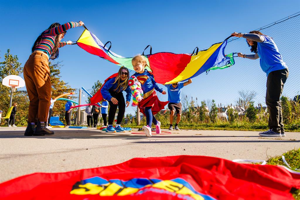 Child crosses underneath a colourful parachute