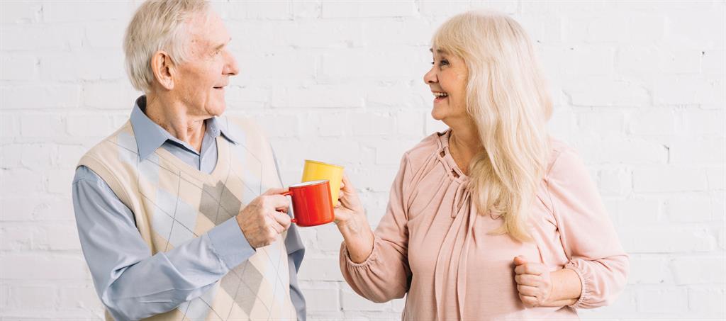 Two grandparents holding mugs of tea